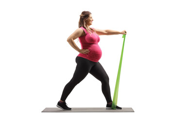 Full length profile shot of a pregnant woman on a mat exercising with a resistance band