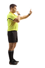 Full length profile shot of an angry sports referee blowing a whistle