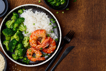 Teriyaki shrimps, rice and broccoli on a wooden table. Asian healthy food. Seafood with garnish. ...