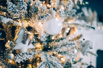 Beautiful snowy Christmas tree against blue background with beautiful ornaments for the holidays. 