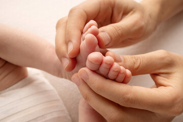 The palms of the father, the mother are holding the foot of the newborn baby. Feet of the newborn on the palms of the parents. Studio photography of a child's toes, heels and feet. 