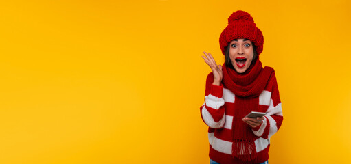 Portrait of happy and excited young modern beautiful woman in red winter hat and scarf while she...