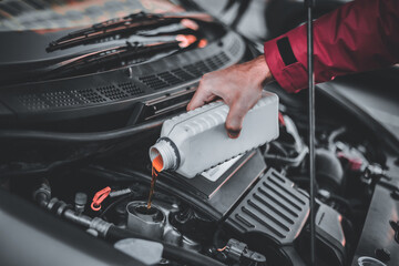 Mechanic changes and pouring oil quality into the engine of the hybrid motor car. Maintenance Gear...