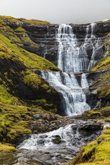 Europe, Faroe Islands. View of waterfall cascading down a hillside in the Faroe Islands.