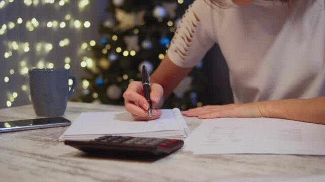 Woman doing budget, estimating money balance for shopping spree in Christmas time. Female accountant paying taxes.