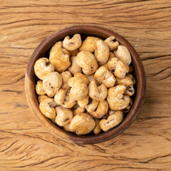 Canjica, hominy or white corn popcorn, sweet popcorn in a bowl over wooden table