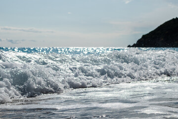 Shining on sun waves splash on sea coast. Blue epic seascape on Lefkada island in Greece. Summer travel to Ionian Sea