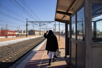 Traveler saying goodbye as she walks along the platform to the platform where she will take the train to her destination. Concept traveler, railroad, railroad, tracks, tourist, station.