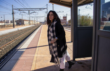 Sexy young woman traveler waiting at the railroad station for the train that will take her to her...