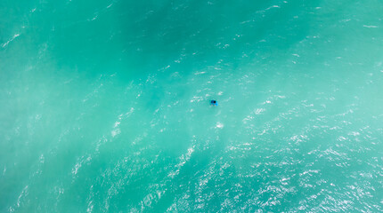 homem em praia com águas cristalinas vista de drone 