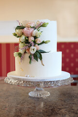 Wedding cake with a bouquet of flowers on a glass tray.