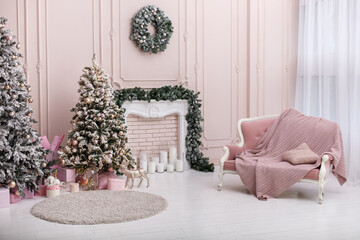 Interior with light walls, fireplace and soft pink sofa decorated for celebrating Christmas. Comfort home in Christmas or New Year Holidays