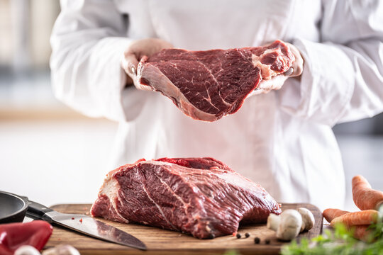 Fresh red meat cut in hands of a chef with chunk of meat on a wooden board