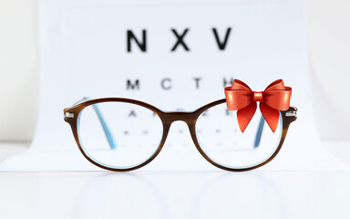 Occhiali da vista e fiocco di nastro rosso isolato su sfondo bianco. Carta regalo per occhiali di Natale.