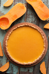 Pumpkin pie with halved butternut squash on old painted wood background