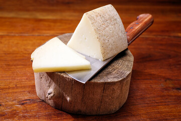 Traditional Italian pecorino aged sheep milk cheese offered as close-up on a wooden board - obrazy, fototapety, plakaty
