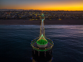 Manhattan Beach Pier with Christmas lights in California. Aerial View from end of Pier at Dawn with city and mountains in background.