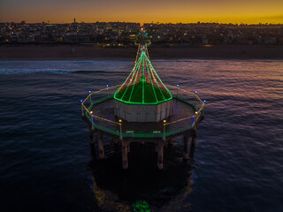Manhattan Beach Pier with Christmas lights in California. Aerial View from end of Pier at Dawn with city in background.
