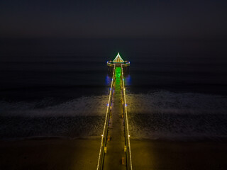 Manhattan Beach Pier with Christmas lights in California. Aerial View from Beach looking out over ocean.