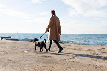 Man walking a Golden retriever on the beach. Concept of walking the dog on holidays. Pet. Black dog
