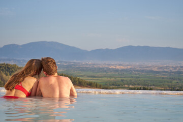  Couple in love swimming in Pamukkale pool on their honeymoon.Newly married couple travel to Turkey. Valentine's Day concept. Lovers at sunset enjoing beautiful