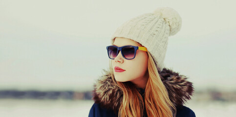 Winter portrait close up of beautiful young blonde woman wearing a hat outdoors