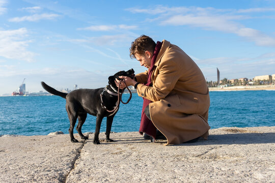 Man cuddling and loving his dog on the beach. Black Golden Retriever. Walking the dog on holidays.