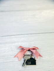 New keys of a house silver with keychain of little house top view with copy space and white wooden background,
