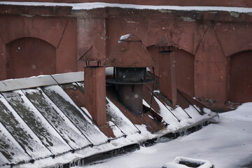 Winter, snowfall. Photo of the old factory. windows and roof of the old factory building. snow-covered old factory