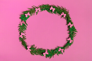 Christmas wreath of fir branches and decorations on a pink background. Flat lay, top view, copy space. festive composition