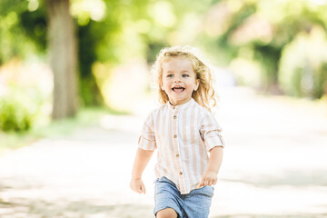 Cute little boy with curly blonde hair playing in park