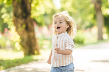 Cute little boy with curly blonde hair playing in park