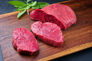 Rohes dry aged Rumpsteak Scheiben vom Bison Rind mit Kräutern angeboten als close-up auf einem...