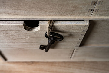 Old key on a rope pinned down by a wooden box