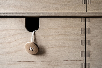 A button on a thread sticks out of a hole in a wooden box