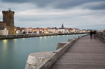 People walking on archway bridge on the Canal of La Chaume