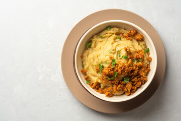 Yellow pea puree or porridge or pudding with meat sauce in bowl on concrete background
