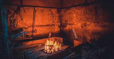 Open fire with sparks in a smithy with tools for forging