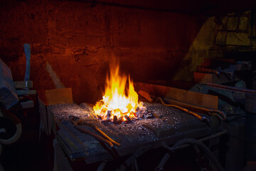 Open fire with sparks in a smithy with tools for forging