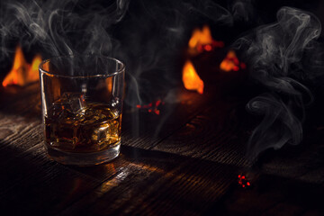 a glass of wiskey on the rocks on a wooden table on the fire