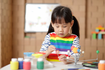 young girl painting swivelling solar system toy at home