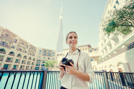 Enjoying travel in United Arabian Emirates. Happy young woman with camera taking photo in Dubai Downtown.