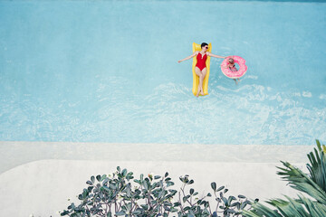 Vacation with a family. Top view of happy young mother and her daughter on the air mattreses having fun in swimming pool.