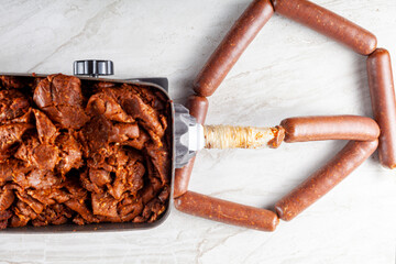 Close up isolated image of homemade sucuk or Sausage that is being stuffed into casing using electrical stuffer device.