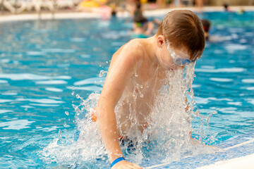 Junge tauchte aus dem Wasser des Pools auf blauem Wasserhintergrund