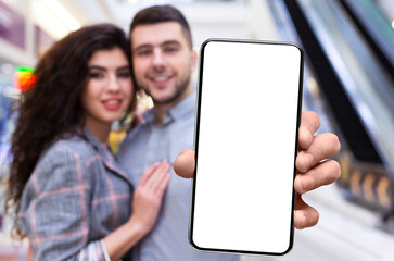 Discount App. Happy young couple showing smartphone with blank screen at camera