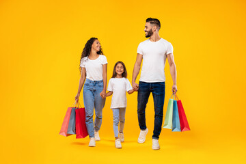 Middle-Eastern Family Shopping Carrying Shopper Bags Walking Over Yellow Background