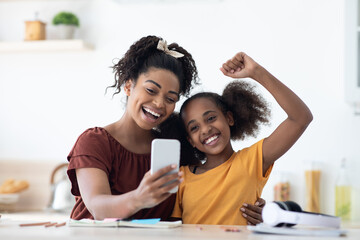 Emotional black mother and daughter taking selfie together, copy space