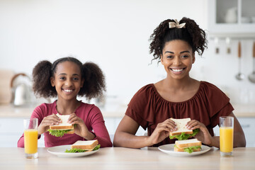 Cheerful african american mother and daughter havign healthy lunch