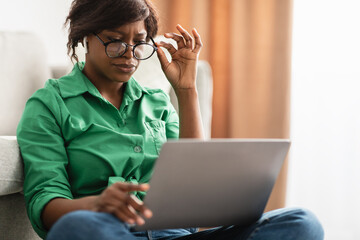 Black Woman With Poor Eyesight Using Laptop Wearing Eyeglasses Indoor